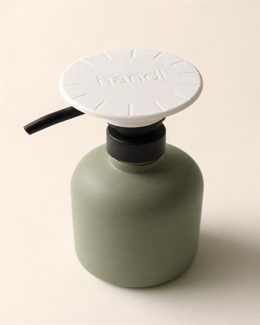 The white PALM press aid fitted over a black pump on a sage-green soap bottle